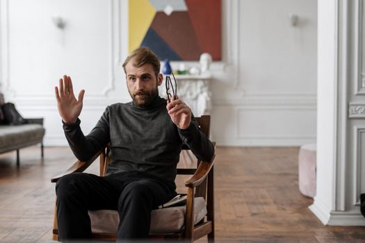 Man consulting with a therapist in a stylish modern office, holding glasses.