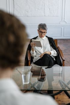 A therapist and patient in a modern office engaging in a reflective consultation session.